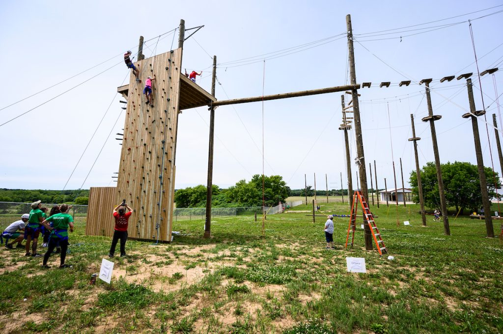 Participants scale the climbing wall at the University of Wisconsin-Madison Adventure Learning Programs (ALPs) ropes course during a grand opening of the facility in Stoughton, Wis., on June 21, 2019.