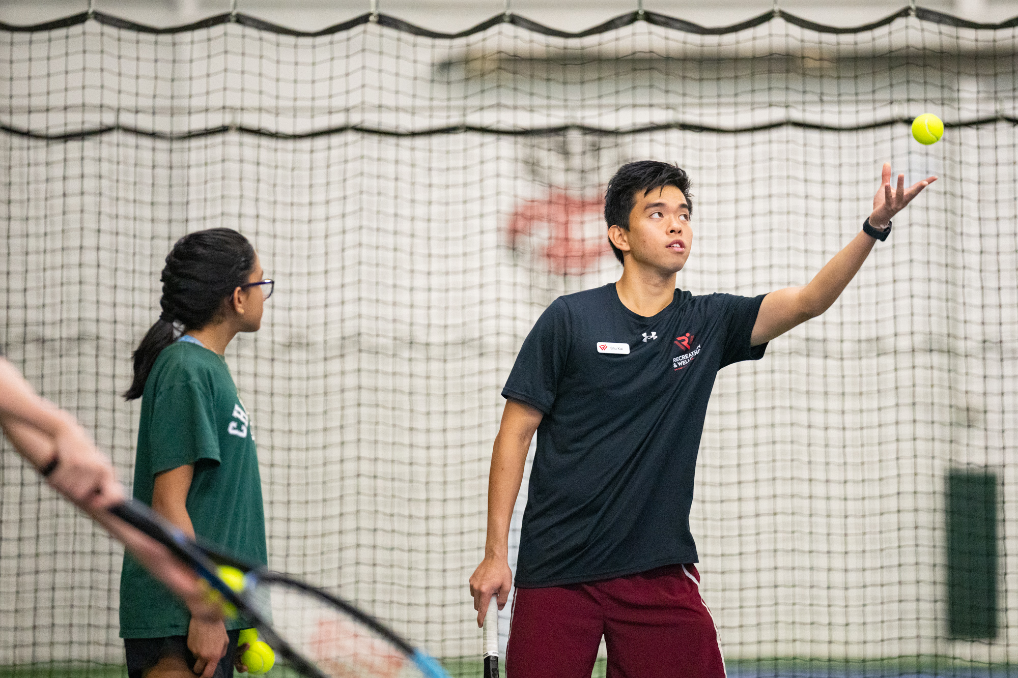 Photo of two tennis players ready to return a serve standing on an indoor tennis court