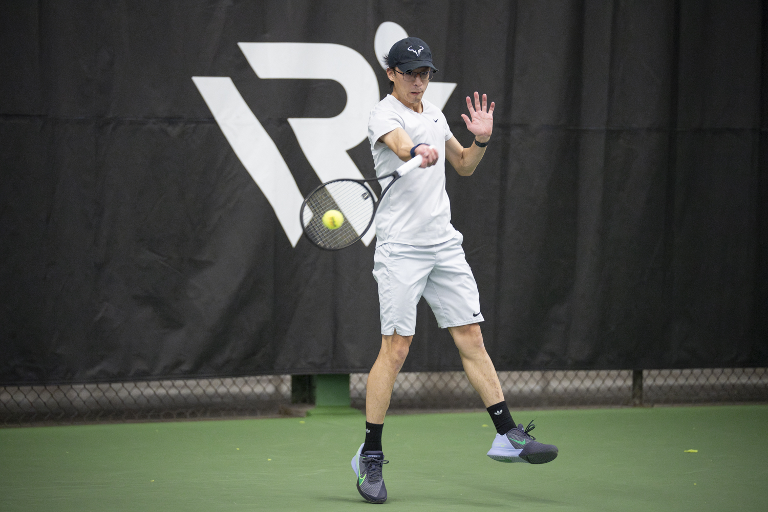 Photo of tennis player returning a ball on an indoor tennis court