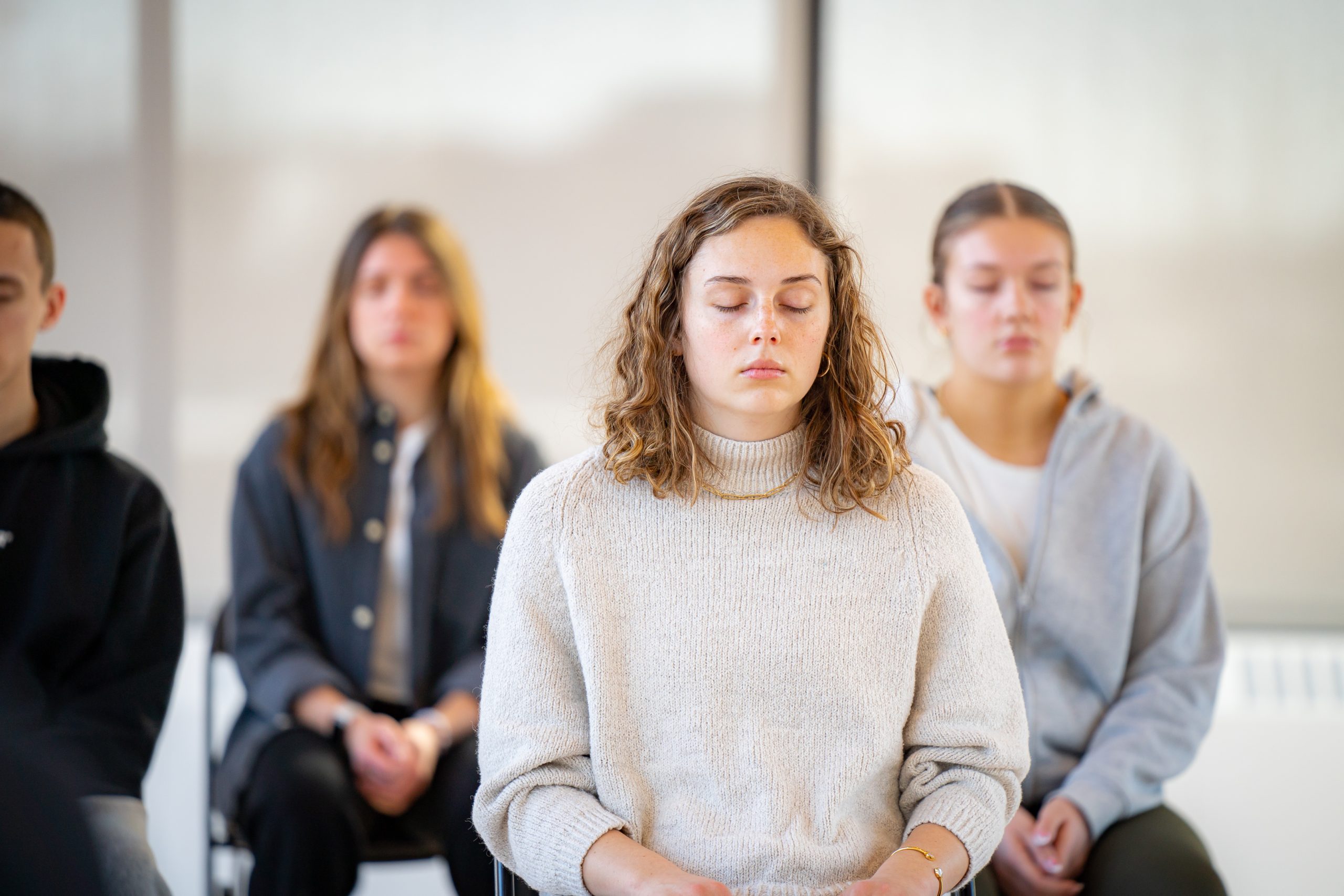 Image of people with their eyes closed meditating.