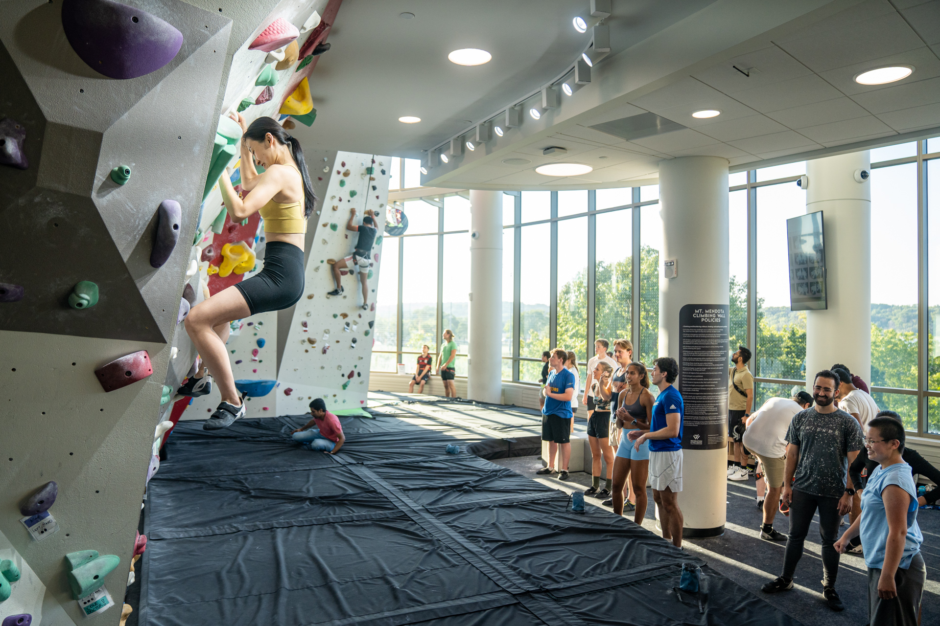 Image of Mt. Mendota that highlights a climber on the wall as well as patrons standing nearby waiting to climb