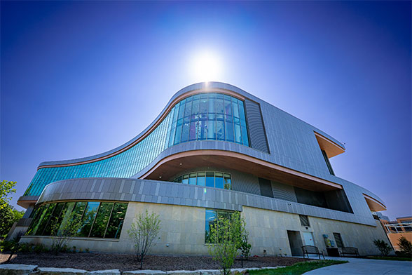 Photo of the exterior of Bakke Recreation & wellbeing Center with the sun shining over the top of the building.