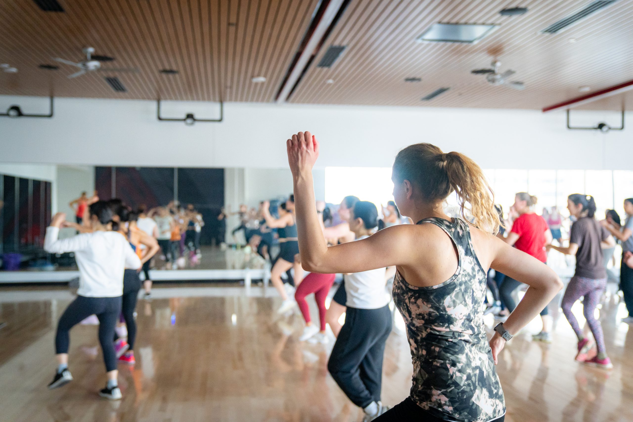 Members participate in a Zumba class in a multipurpose studio room.