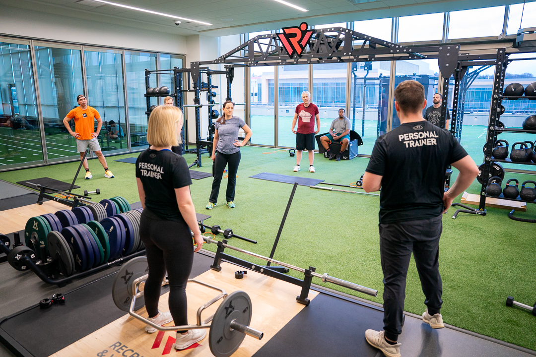 Personal trainers instructing a class on weight lifting.