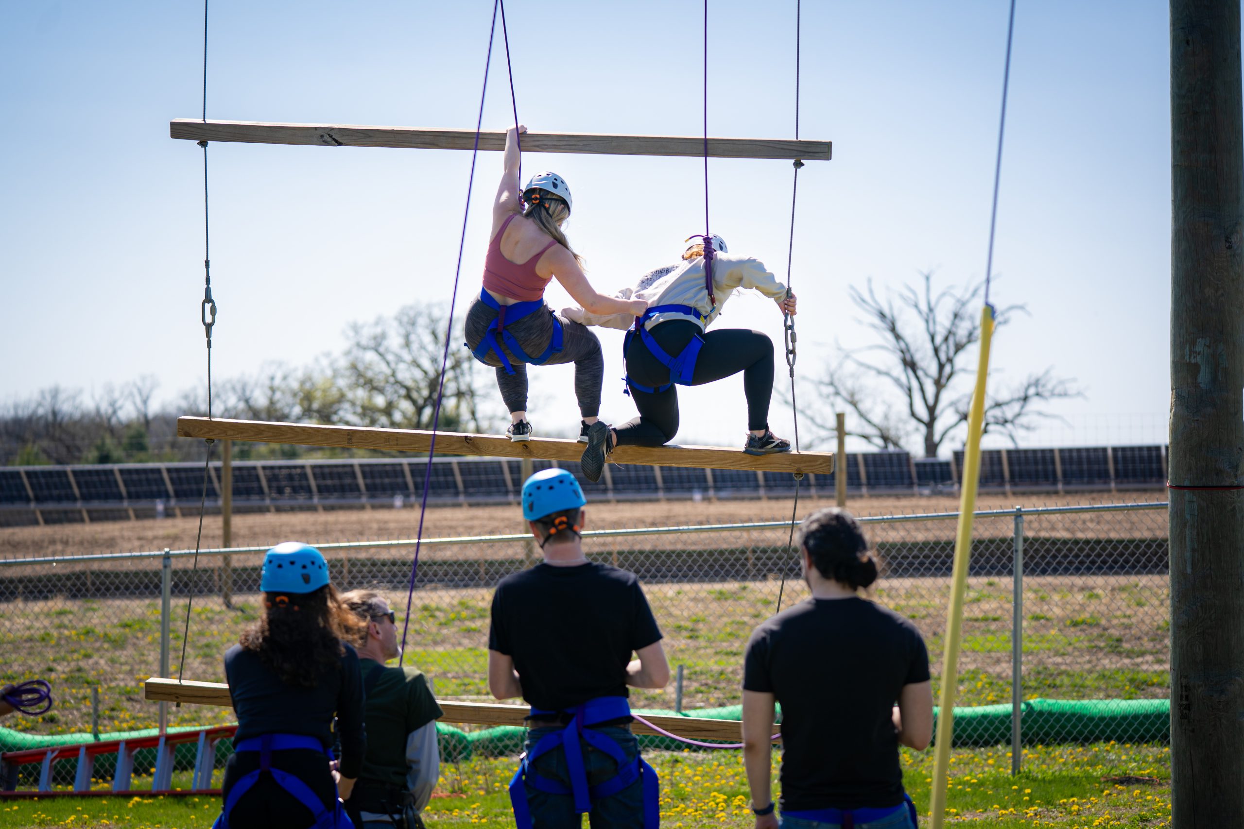 People helping each other on a ropes course.