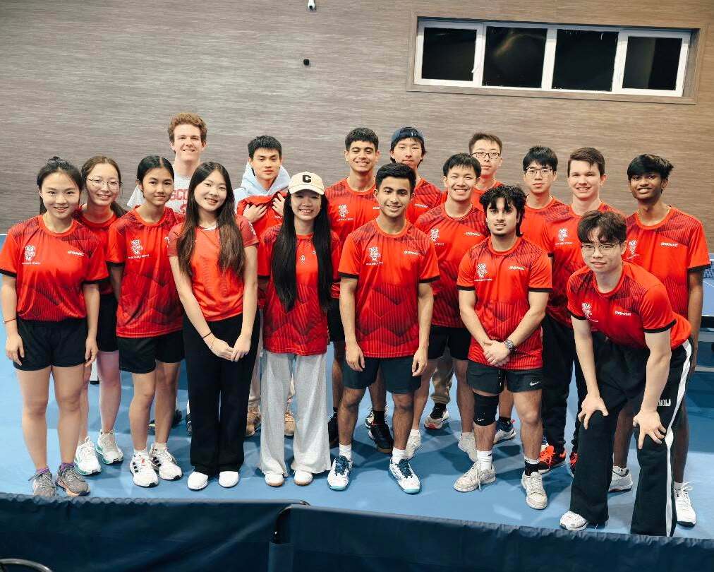 The Table Tennis team is pictured indoors wearing red shirts. 