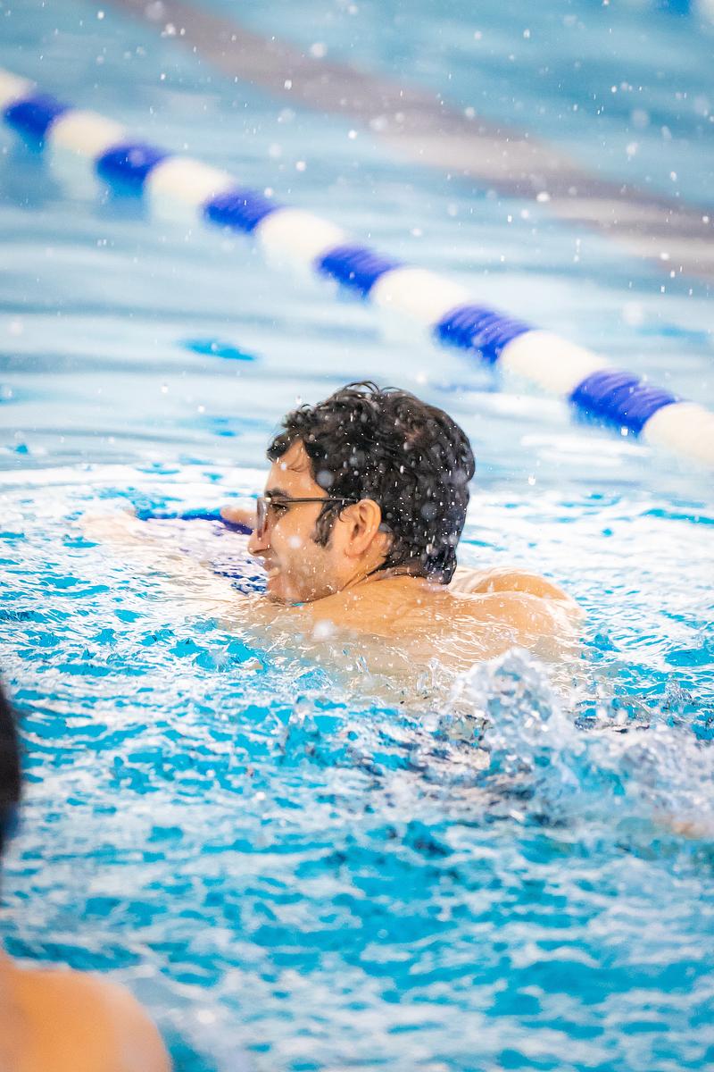 A man swimming with a kick board in a pool.