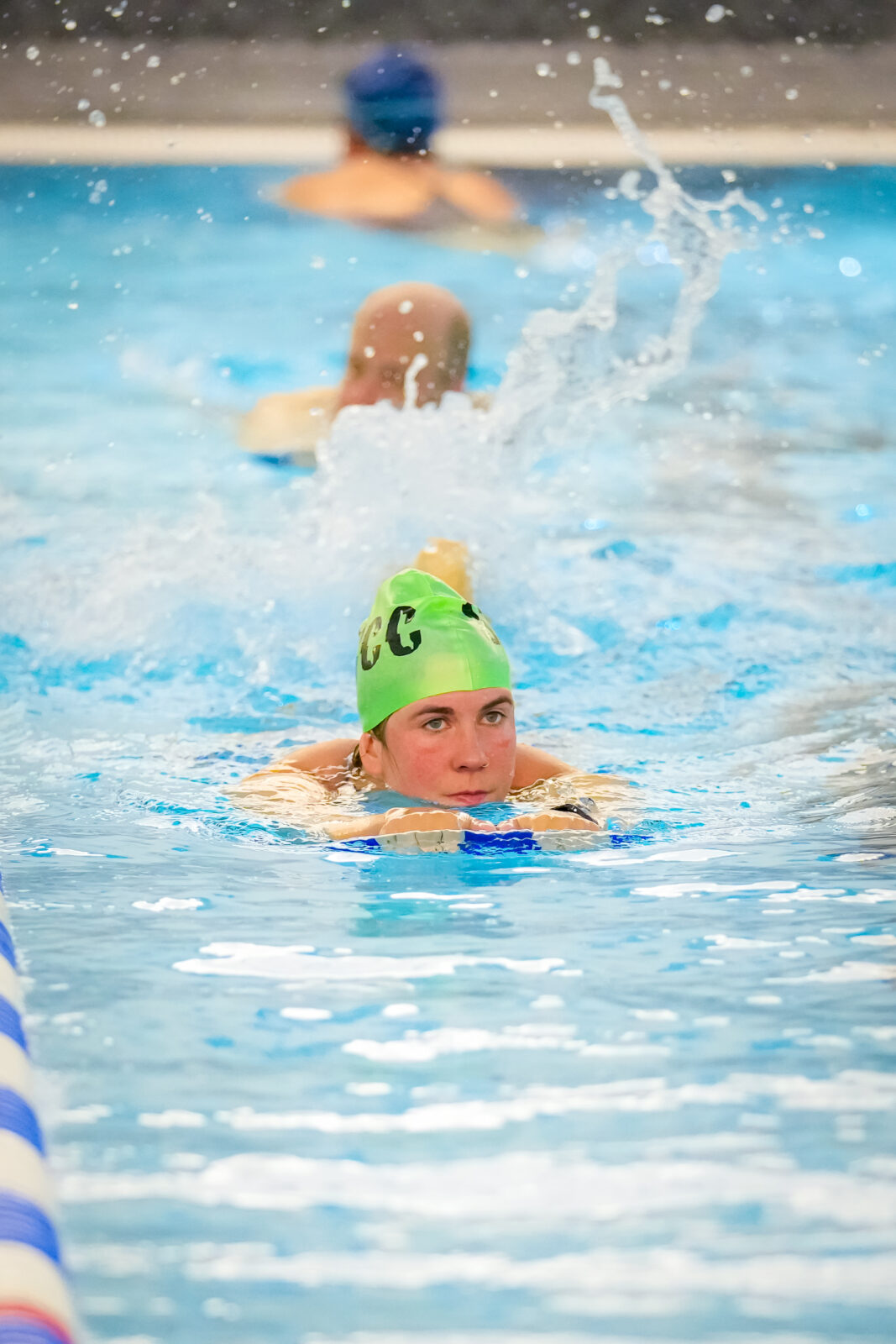 A swimmer kicking with a kick board in a pool.
