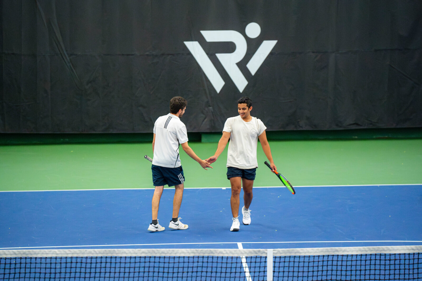 Two men high fiving on a tennis court.
